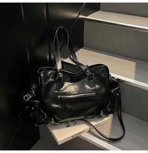 Detail of black glossy faux leather tote bag with silver hardware and multiple pockets
