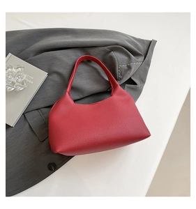 Close-up of red lychee pattern leather on a minimalist rivet hollow shoulder bag
