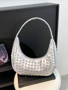 Silberne Metallic-Punk-Hobo-Tasche mit Nieten-Details auf weißem Tischhintergrund