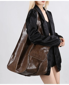 Detailed view of deep brown large leather tote bag worn by a model in studio