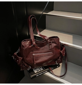 Macro detail of dark burgundy tote bag showing glossy texture and metal zipper pockets