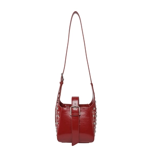 Sac seau en cuir verni rouge avec clous argentés et boucle métallique sur fond blanc
