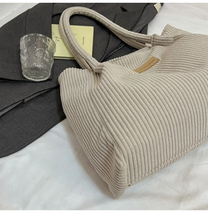 Detailed close-up of cream corduroy tote bag texture with brown leather logo patch