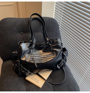 Detail of black motorcycle tote bag with oily leather texture and metal buckles