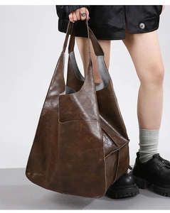 Detail view of large dark brown leather tote bag with stylish folded stitching and side pocket