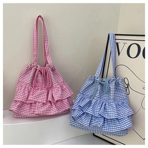Close-up of pink and blue gingham canvas tote bags featuring tiered ruffle trim details