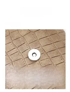 Close-up of silver magnetic clasp on brown crocodile pattern leather handbag