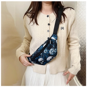 Détail du sac de poitrine tendance avec imprimé fleurs bleues et crâne et zip métallique