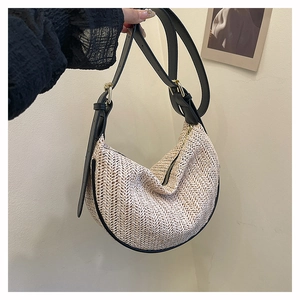 Dettaglio della borsa dumpling a righe con texture intrecciata e tracolla in pelle nera