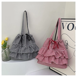Detail of checkered tote bags with layered ruffles and drawstring closure on display