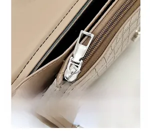 Detail of smooth silver zipper and crocodile embossed leather on khaki evening bag