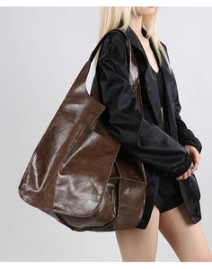 Model wearing a large dark brown faux leather tote bag with vintage texture and wide strap