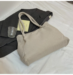 Detail shot of a large beige corduroy tote bag styled on a bed for daily commute