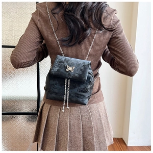 Close-up of black velvet backpack with silver butterfly hardware and chain straps