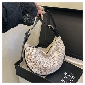 Dettaglio della borsa a mezzaluna intrecciata beige con tracolla in pelle nera e fibbia