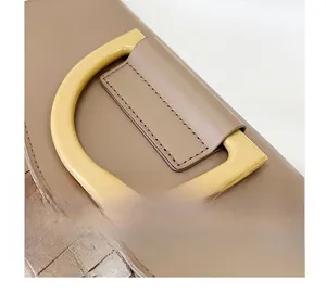 Detail of khaki crocodile pattern leather bag featuring a yellow resin D-ring handle