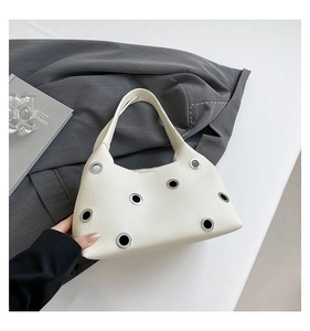 Detail of cream white leather shoulder bag with large silver metal eyelet studs