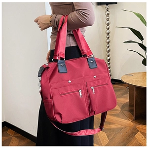 Detailansicht der roten Nylon-Tragetasche mit Reißverschlusstaschen und Metallbeschlägen