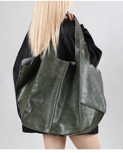 Detail of dark green vintage tote bag showing soft faux leather texture and side pocket