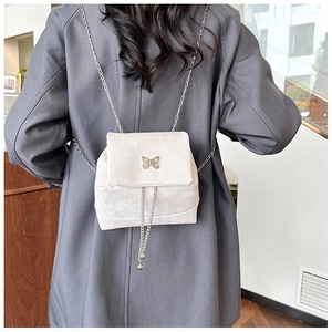 Detail of cream velvet mini backpack with silver bow buckle and elegant metal chain strap