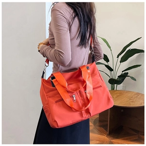 Detailansicht der orangen Nylon-Schultertasche mit mehreren Taschen an einem Modell
