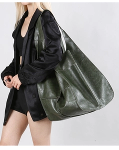 Dark green vintage soft leather tote bag worn by a model against a grey backdrop