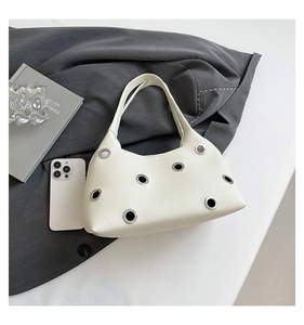 Detail of rivet cut-out cream leather shoulder bag with silver eyelets and pebble texture
