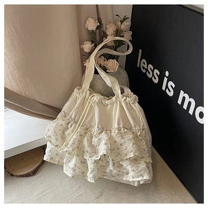 Detalle de bolso tote floral crema con volantes en capas y cierre de cordón