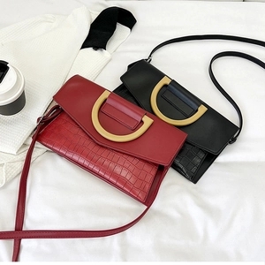 Close-up of crocodile-embossed envelope bags with elegant gold D-shaped buckles