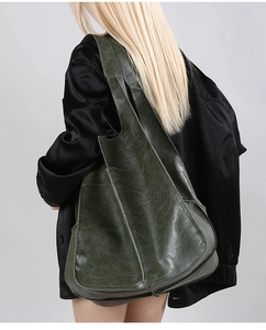 Side view of large dark green hobo bag in soft leather texture on female model