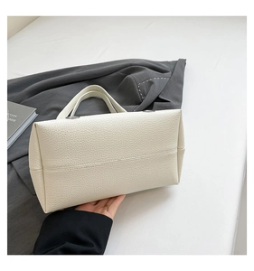 Detailed side view of beige litchi grain leather underarm bag with silver ring hardware