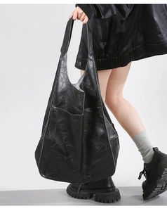 Detail of vintage black oversized tote bag showing side pocket and soft leather texture