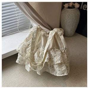 Detalle de bolso tote de lona crema con volantes florales dobles y cierre de cordón ajustable