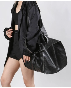 Close-up of oversized black tote bag in distressed leather with natural fold texture