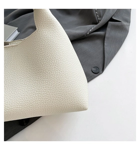 Detail of cream white pebbled leather shoulder bag with sleek stitching and chic rivet design