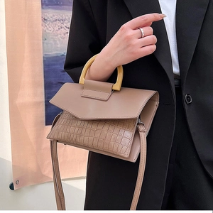 Detail of elegant crocodile texture brown clutch bag with unique yellow U-shaped handle