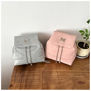 Detail of sweet bow metal buckle and suede texture on silver and pink mini backpacks