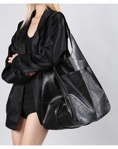 Side view of a vintage black leather tote bag worn by a model to show large size and texture