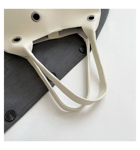 Detailed close-up of cream lychee grain leather with silver metal grommet studs