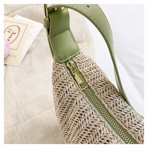 Dettaglio macro della borsa in paglia beige con finiture in pelle verde e zip dorata
