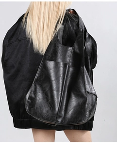 Large black matte soft leather tote bag with external pocket shown on shoulder