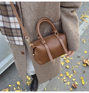 Brown pleated Boston bag styled with long brown wool coat on an autumn street setting