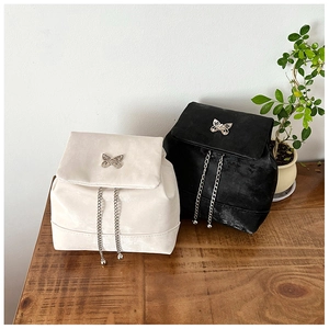 Close-up of velvet backpacks in black and white with metallic butterfly and chain details