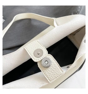 Detail view of the beige rivet bag showing the metal magnetic closure and pebble leather texture