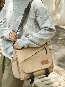 Outdoor shot of a khaki large capacity crossbody bag with adjustable black strap