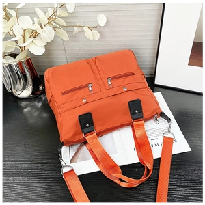 Detail der leuchtend orangefarbenen Nylontasche mit Reißverschlussfächern und Griffen