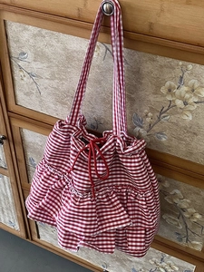 Red and white checkered canvas tote bag with ruffle trim and drawstring closure