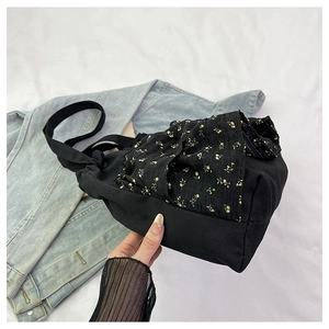 Detalle de bolso de lona negro con fruncido de flores amarillas y volantes