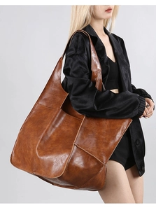 Detail view of large brown vintage tote bag with premium leather texture on a model
