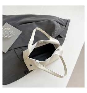 Top view of cream hollowed rivet underarm bag showing interior space and silver eyelets